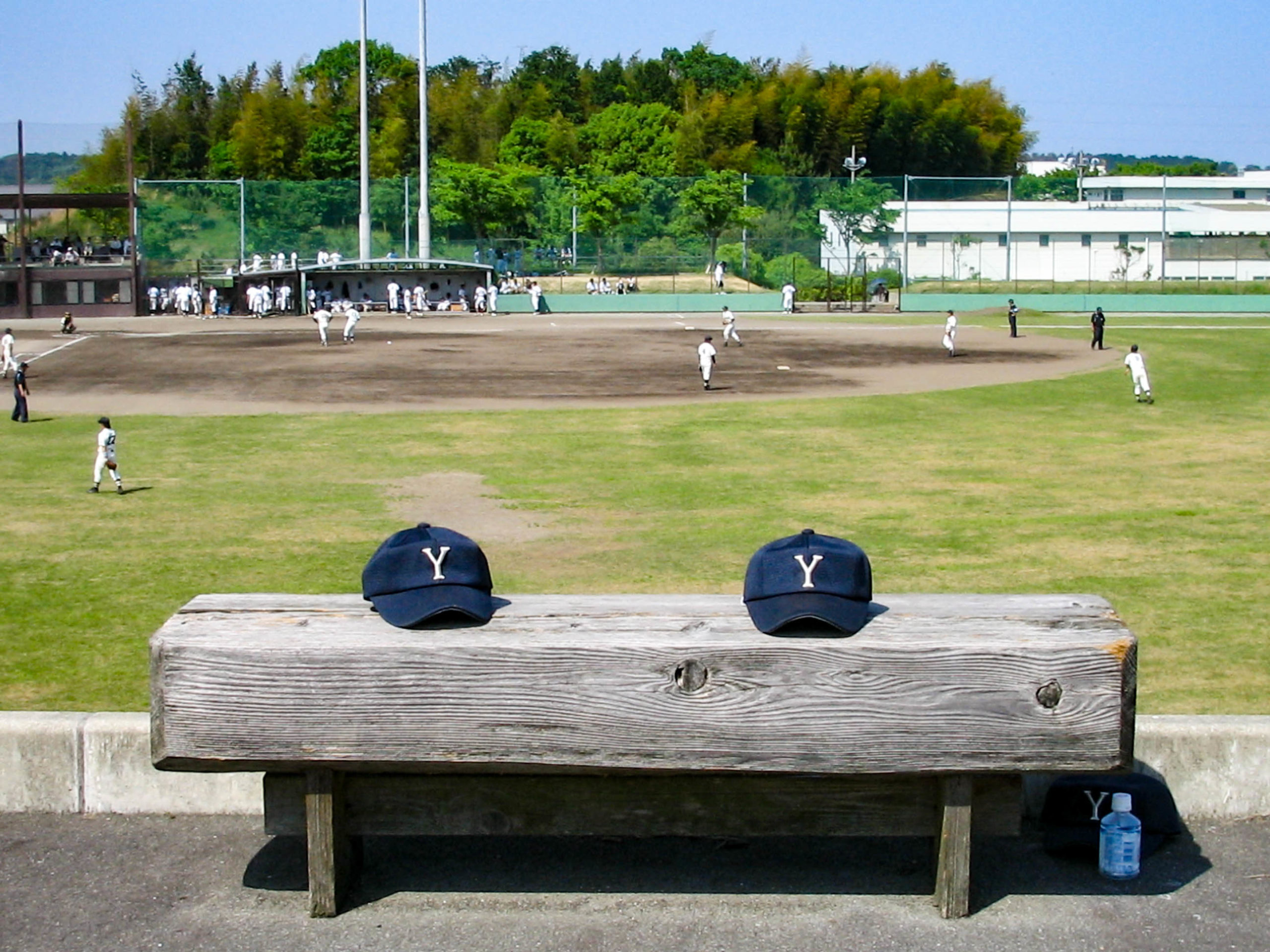 ベンチに置かれた2つの野球帽の写真